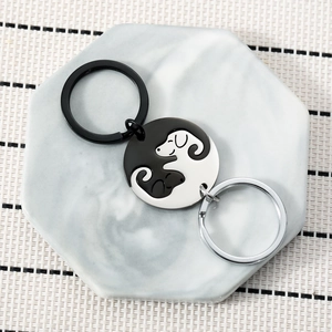 Yin Yang puppy dog keychains in black and silver finishes on marble background