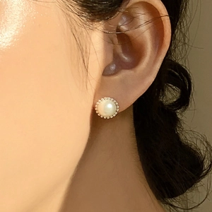 Close-up of a 925 sterling silver pearl stud earring with gold beaded edge on ear