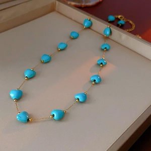 Detail of bohemian gold chain necklace with turquoise heart beads on a display tray