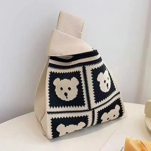 Detail of knitted knot bag with cute black bear pattern on beige fabric