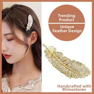 Detailed view of a handmade gold feather hair clip with sparkling white rhinestones