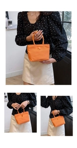 Détail du mini sac seau en nylon orange avec doubles poignées et design minimaliste de couleur unie