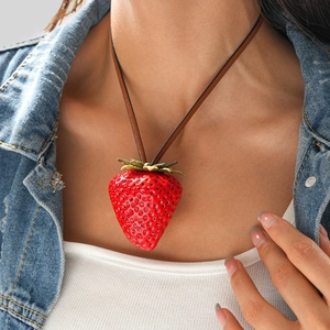 Detail shot of a creative red strawberry pendant necklace with golden leaves on a model