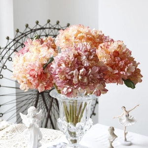 Detailed view of artificial pink hydrangeas in a glass vase with retro home decor