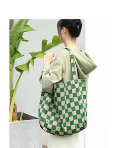 Close-up of a green and beige checkerboard canvas tote bag with wide shoulder strap