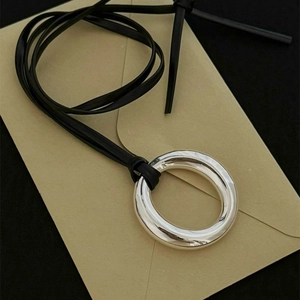 Y2K minimalist silver ring pendant necklace with black leather cord on beige envelope