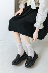 Detailed view of white lace mesh crew socks paired with black loafers and a skirt