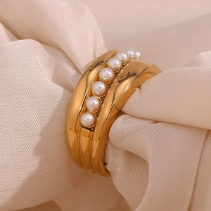 Macro shot of 18K gold plated wide ring with elegant white pearls in beige fabric