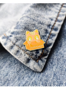 Close-up of cute enamel cat pin with Introvert text on blue denim jacket collar