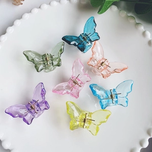 Colorful acrylic butterfly hair clips in translucent pastel shades on a white lace plate