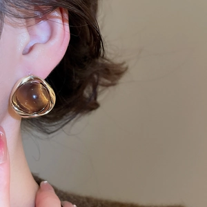 Close-up of model wearing 18k gold plated round earrings with brown tiger eye stones