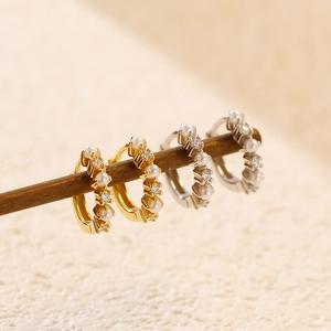 Detailed shot of S925 earrings with pearls and diamonds hanging on a natural wooden branch