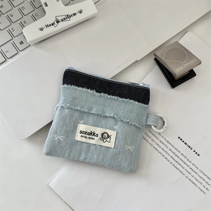 Detail of denim coin purse with cute dog patch and metal carabiner in a lifestyle setting