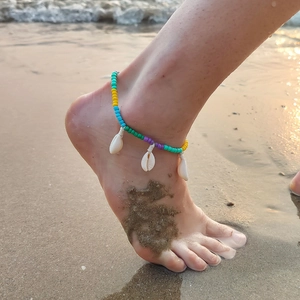 Bohemian seashell anklet with colorful beads and white shells on a sandy beach