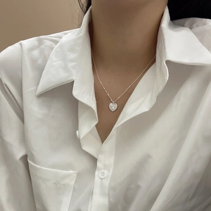 Close-up of S925 sterling silver heart pendant with textured fold detailing on model
