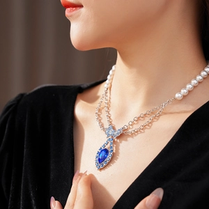Double-layered pearl necklace with a vintage blue gemstone pendant on a female model