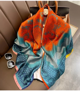Détail de la texture du foulard en soie avec motif floral bleu et orange sur canapé