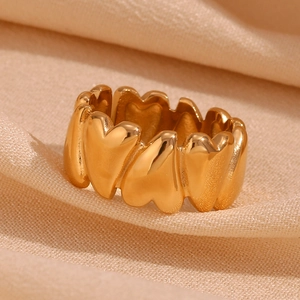 Macro view of gold 18K plated heart-shaped linked rings on beige fabric