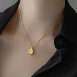Détail d'un collier doré 18K avec pendentif goutte et étoile porté par un mannequin