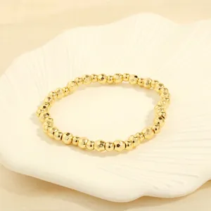 Detailed macro view of faceted golden beaded bracelet on a white scallop ceramic plate