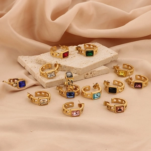Gold chain drop earrings with rectangular multicolor zircons on a beige textured stone