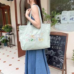 Détail de la broderie Lucky Suzuka et des étoiles colorées sur le sac fourre-tout vert