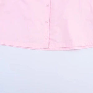 Detailed close-up of pink poplin shirt featuring resin buttons and flat hem stitching