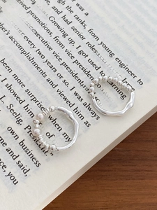 Detailed close-up of S925 silver bead rings with white pearls on a vintage book page