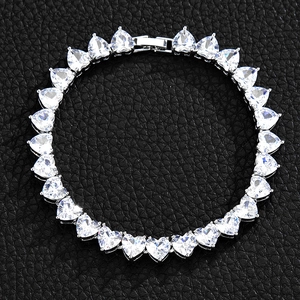 Close-up of silver tennis bracelet with heart-shaped crystals on black leather background
