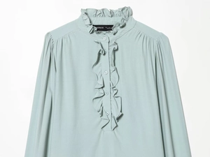 Detail of light blue ruffle collar and placket on a woven long-sleeved shirt