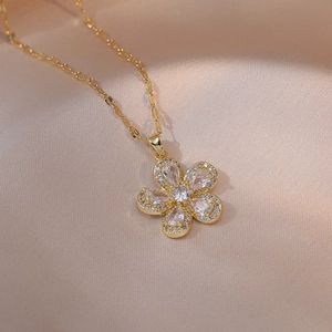 Elegant gold flower necklace with white zircon petals on a luxurious silk background