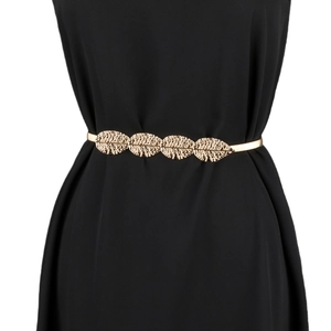 Detailed close-up of golden leaf-shaped metal elastic waist belt on black dress garment