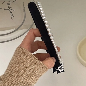 Detailed close-up of premium white pearls on a black velvet headband with elegant texture