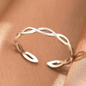Macro shot of silver bohemian style twisted rope ring on premium brown silk fabric