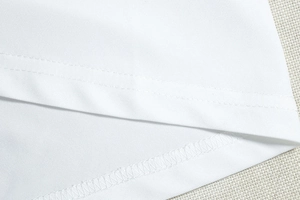 Dettaglio di un abito in cotone bianco con orlo a doppio ago e cuciture tagliacuci