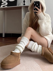 Detail of chunky knit leg warmers in cream styled with platform suede boots for winter