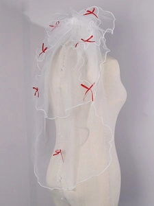 Detail view of multi-layer white bridal veil with red bow and pearl embellishments
