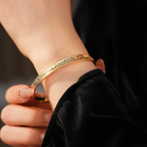Close-up of golden metal bracelet with hexagonal honeycomb textured pattern and metallic luster