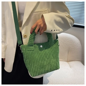 Detail of green corduroy bucket bag texture and white buckle with adjustable strap