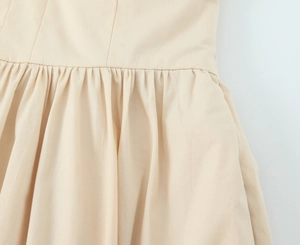 Close-up of beige poplin midi dress showing waist seam details and fine pleating work