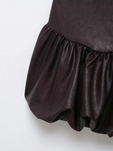 Détail du tissu en cuir marron foncé montrant la texture plissée de l'ourlet