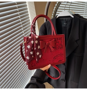 Macro shot of red lace handbag featuring bow detail and silk scarf wrapped on handle