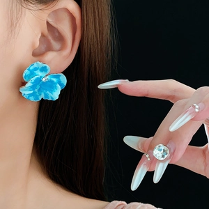 Primo piano di orecchini a fiore di viola del pensiero blu con diamante su una modella