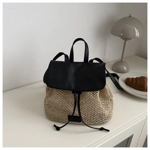 Détail du sac à dos en paille avec rabat en cuir noir et cordon de serrage pour l'été