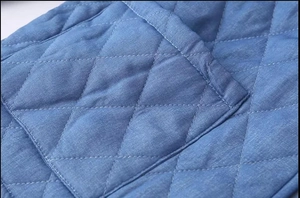 Macro detail of blue quilted diamond pattern and double stitching on the jacket fabric