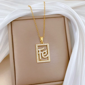 Detailed close-up of golden hollow square necklace with Fe pendant and sparkling crystals