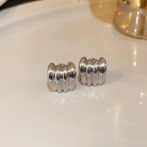 Macro shot of silver textured hoop earrings with shell-like ribbed metal details