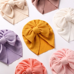 Close-up of ribbed knit baby turbans with large bows in various pastel colors