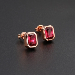 Macro detail of rectangle red ruby stud earrings with rose gold plated borders