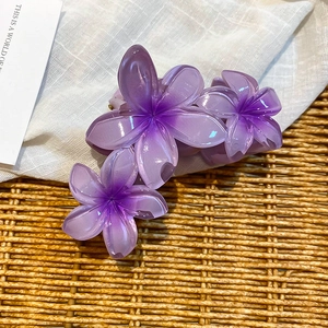 Detail of purple acrylic floral hair claw clip on a rustic woven background for summer
